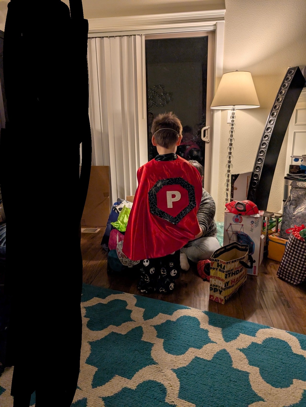 Child in a superhero costume with a red satin cape featuring a large 'P'