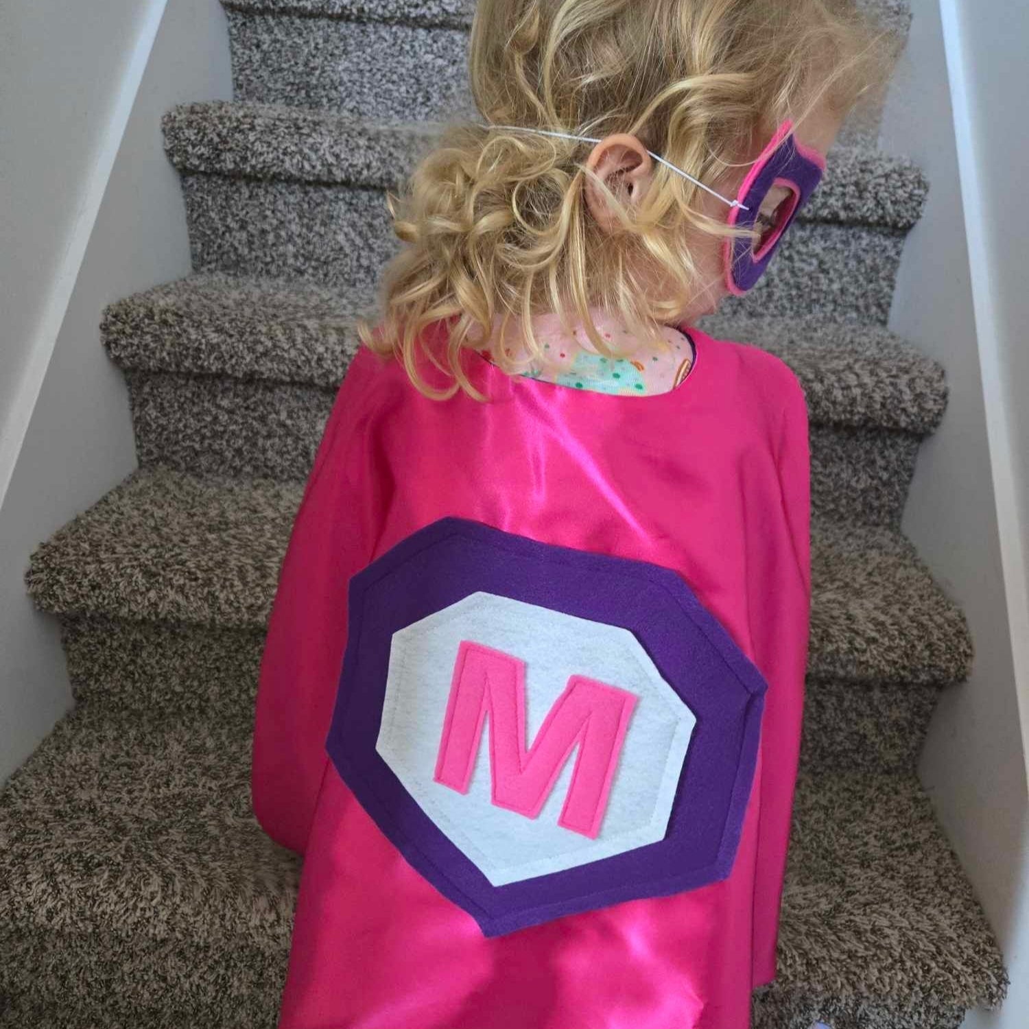back of pink cape featuring the child's first initial sewn by CreativeCapes.com in the USA