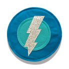 A dark aqua colored felt shield with a silver bolt design in the center, approximately 10 inches in diameter, with a soft elastic handle on the backside.