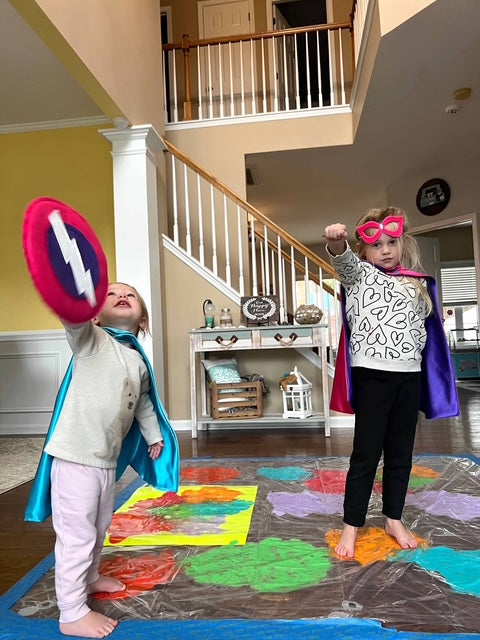 girls pretending to be superheroes in their house with Creative Capes masks, shields and capes