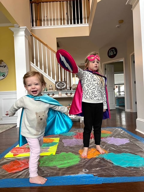 girls inside play superhero in blue and pink personalized capes that are made for active play