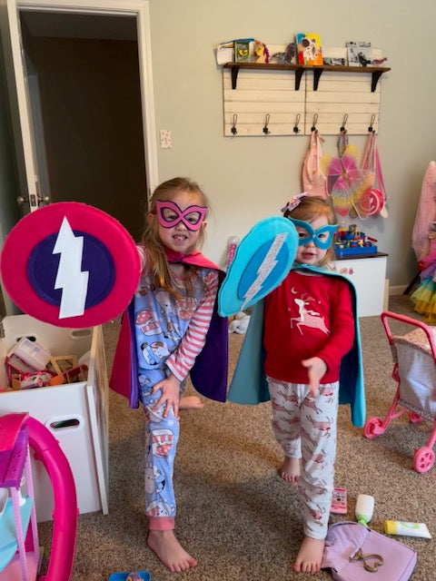 girls in playroom enjoying playing superhero in their custom capes by Creative Capes