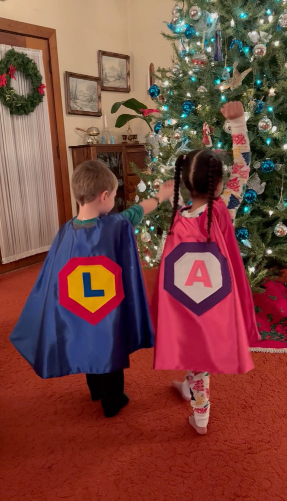 boy and girl at Christmas wearing their satin super hero costumes by Creative Capes