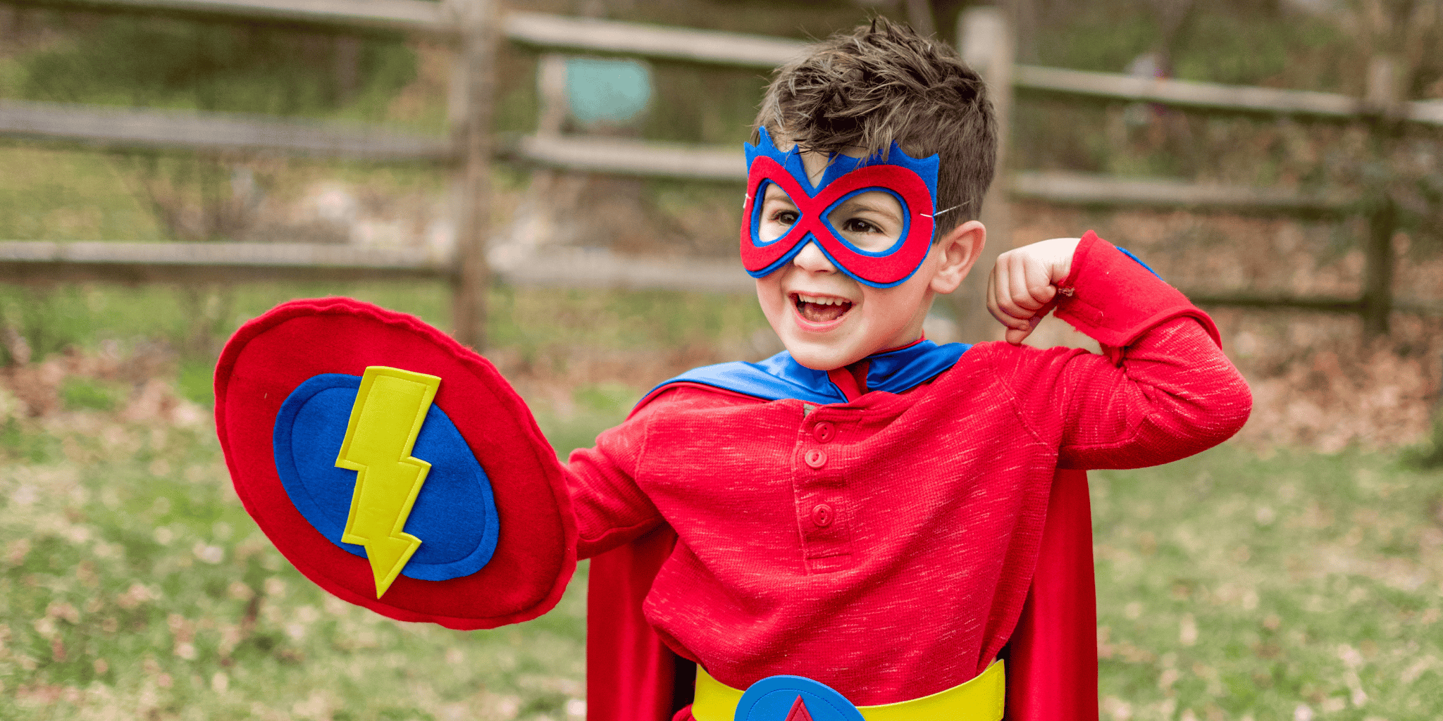 Boy in red, blue and yellow superhero costume with mask, shield and cape having pretend play in his Creative Capes outfit, quality materials made for active kids