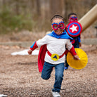 kids active play without screens using personalized blue, red and yellow superhero costume set, featuring the child's first initial on the super hero cape, quality dress-up costume kit includes a lined satin cape, shield, mask, belt, and wrist cuffs, handmade by Creative Capes in USA to inspire imaginative play and confidence. Play without screens creates a healthy childhood.