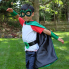 boy playing in green and black personalized superhero costume set, child's first initial on the super hero cape, dress-up costume kit - lined satin cape, shield, mask, belt, and wrist cuffs, Handmade by Creative Capes in USA, inspire imaginative play and confidence, play without screens creates a healthy childhood