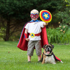 boy in blue, red and yellow superhero costume set, featuring the child's first initial on the super hero cape, quality dress-up costume kit includes a lined satin cape, shield, mask, belt, and wrist cuffs, handmade by Creative Capes in USA to inspire imaginative play and confidence. Play without screens creates a healthy childhood.