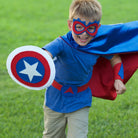 boy outdoors running in USA theme superhero costume in red, white and blue. Hero costume made with quality satin for active play,  handmade by Creative Capes in the USA