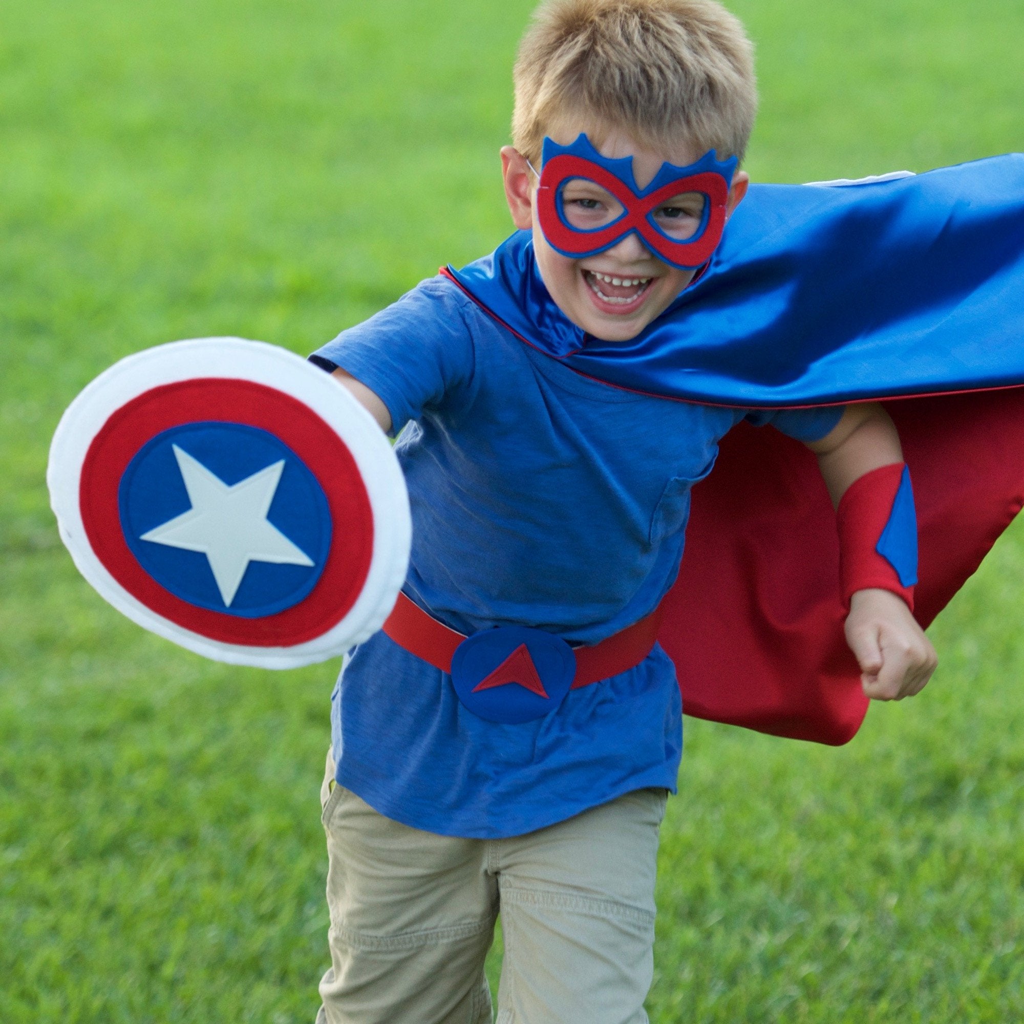 boy outdoors running in USA theme superhero costume in red, white and blue. Hero costume made with quality satin for active play,  handmade by Creative Capes in the USA