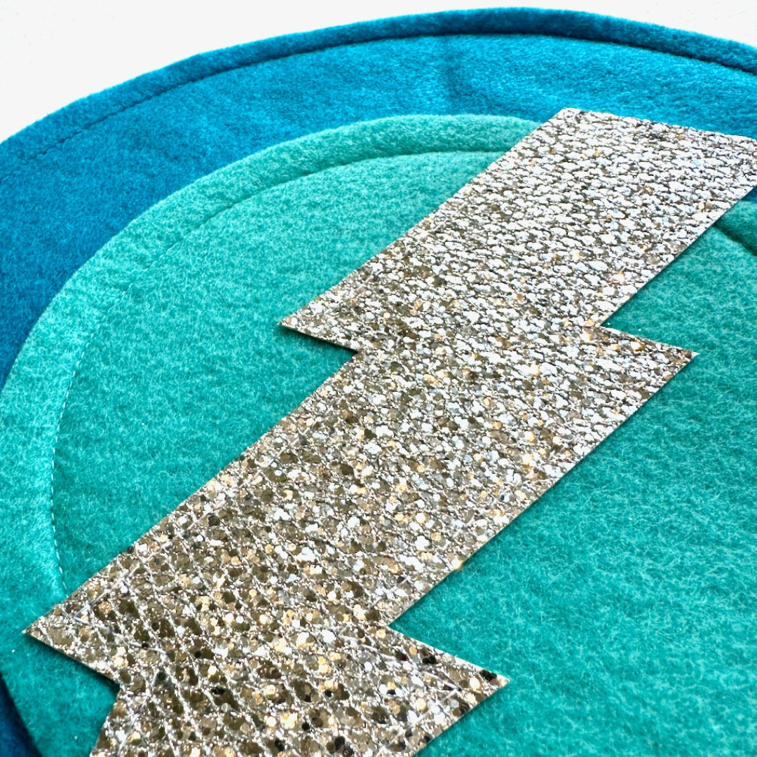 close up of Creative Capes felt aqua shield  with silver bolt