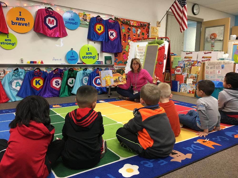 preschool teacher reading Giraffes Can't Dance to students who are getting personalized capes and masks for Superhero Day