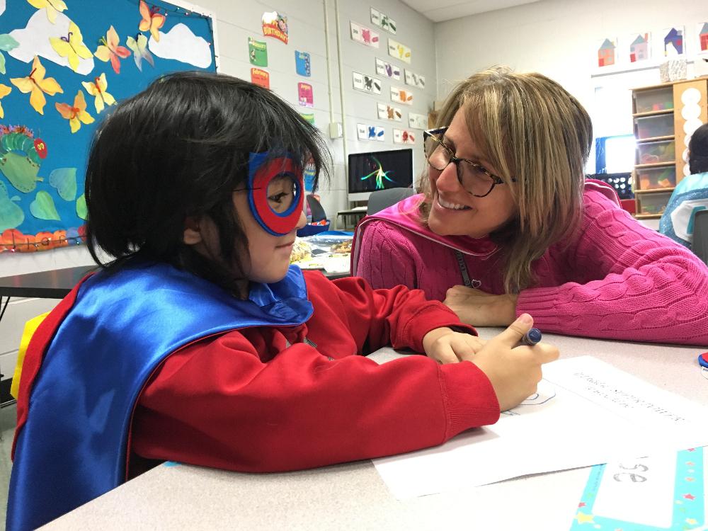student and teacher discussing his unique strengths as they wear their custom capes by Creative Capes